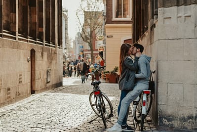 romantic couple with bicycles kissing on old street
