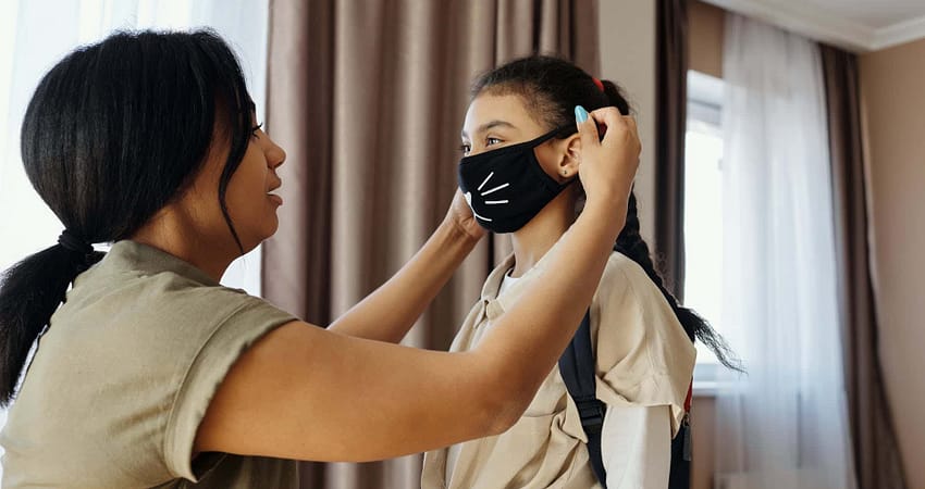 mother putting a face mask on her daughter