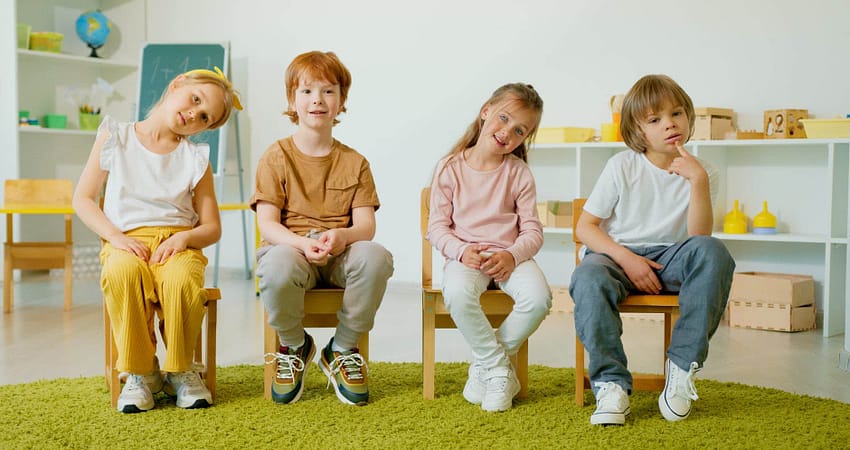 children sitting on wooden chairs